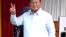 Capres 02 Prabowo Subianto usai mencolos tampak mengenakan kemeja biru muda khas kampanye sambil mengacungkan dua jari bertinta.