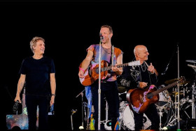 (Chris Martin tertawa/ Foto: Twitter @kolonigigs)